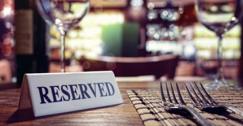 Restaurant reserved table sign with places setting and wine glasses ready for a party
